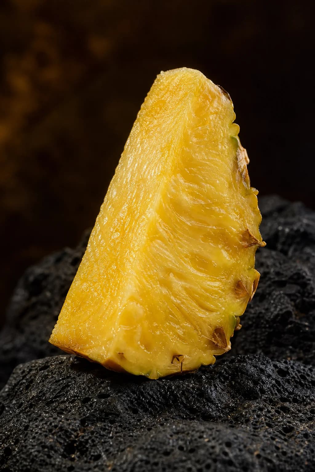Golden pineapple flesh and textured rind on dark stone