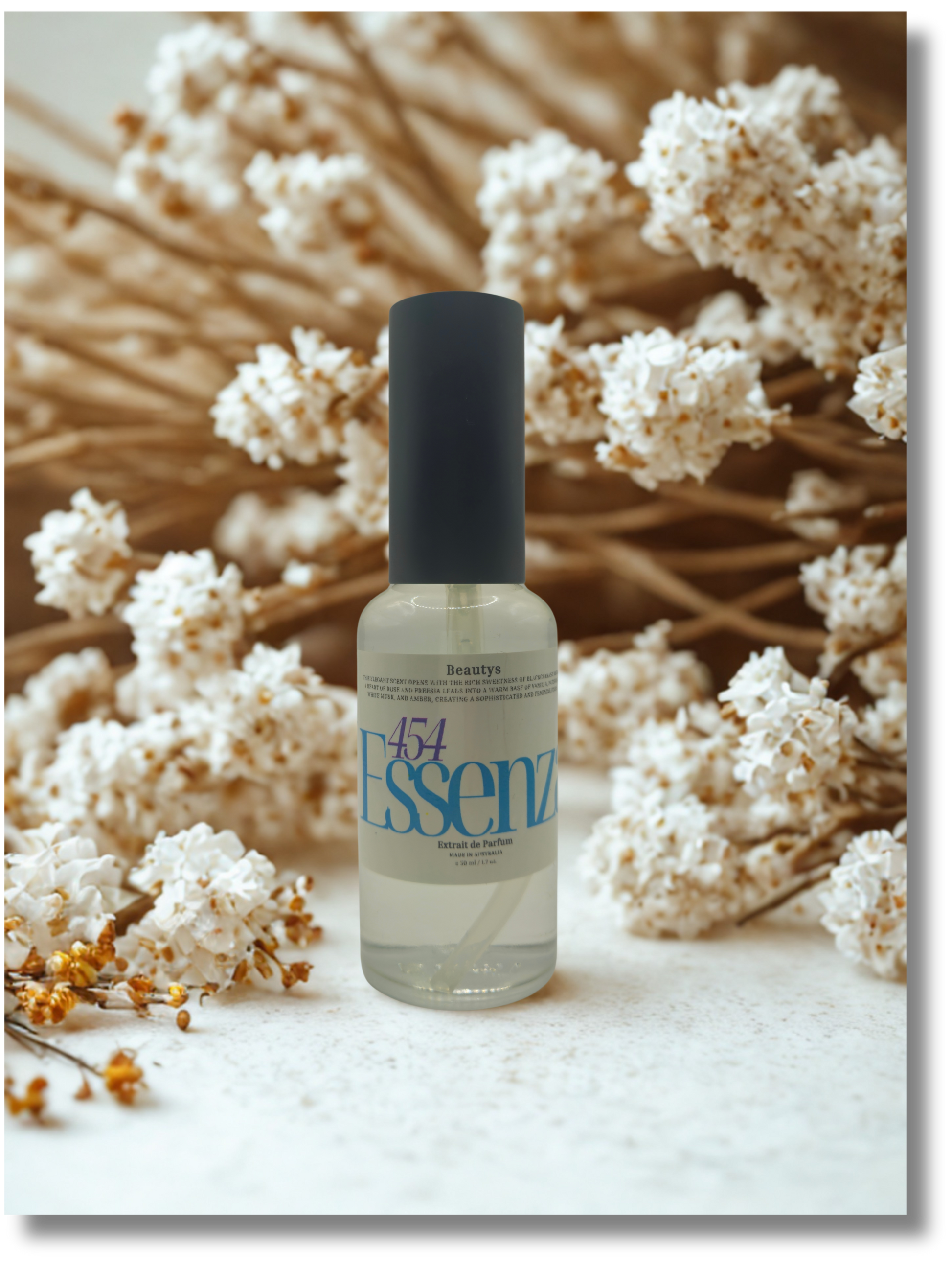 Bottle of Essenz with a black cap on a white surface with dried flowers in the background